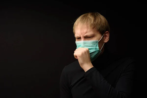 Middle aged man with medical face mask portrait close up illustrates pandemic coronavirus disease on dark background. Covid-19 outbreak contamination concept.