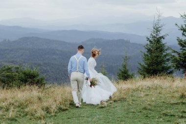 Gelin ve damadın dağlarda çekilmiş bir fotoğrafı. Boho tarzı düğün fotoğrafı..