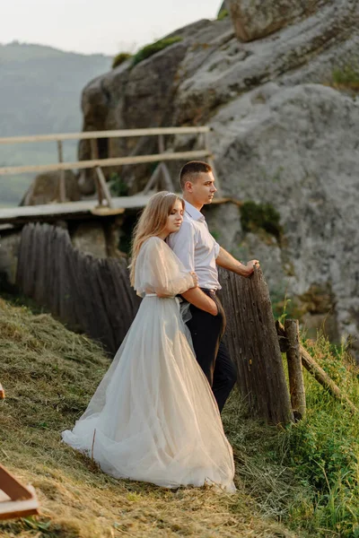 Photoshoot of a couple in love in the mountains. The girl is dressed like a bride in a wedding dress.