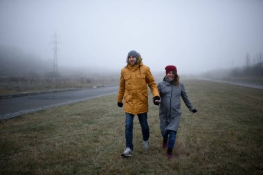 Sevgili hamile çift, sonbaharın sonlarında şehir dışında yürüyorlar..