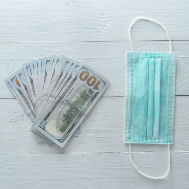 Tıbbi eldivenler, para, antiseptik ve tıbbi maske yukarıdan beyaz ahşap bir arka planda.