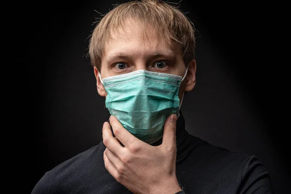 Middle-aged man in a medical mask is suffocating. It\'s hard for him to breathe. Coronavirus threat concept.