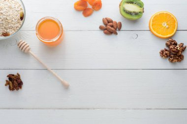 Kivi, bal ve kurutulmuş kayısılar beyaz ahşap bir masada yatar. Sağlıklı kahvaltı..