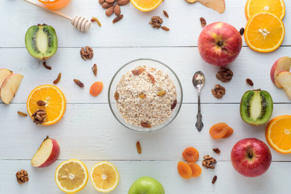 A plate with muesli surrounded by apples, kiwi, dried fruits, oranges and apples. Healthy eating concept.