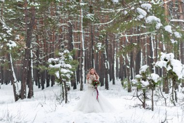 Karlı ormanda bej örülmüş kazaklar içinde gelin ve damat. Yeni evliler alınlarına dokunuyor. Kış düğünü. Boşluğu kopyala