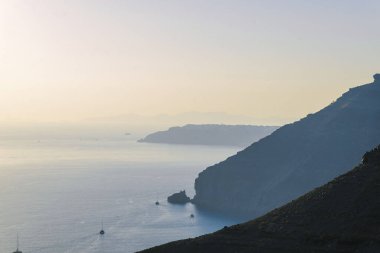 Santorini 'den deniz manzarası ve uçurumlar. Yatlar çok uzaklara gidiyor..