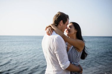 Santorini adasında denizin arka planında yürüyen genç bir çift.