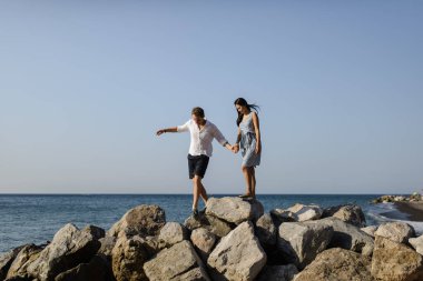 Santorini adasında denizin arka planında yürüyen genç bir çift.