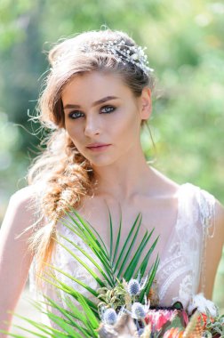 Pembe gelinlikli mutlu gelin. Kız elinde bir düğün buketi tutuyor. Ormanda Boho tarzı bir düğün töreni..