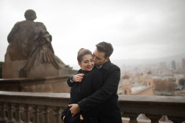 Genç, güzel, aşık İspanyol çift Ulusal Katalonya Sanat Müzesi 'nin önünde yağmurda sarılıyor. Barcelona 'da İspanya Plaza' nın arka planına karşı çekilmiş..