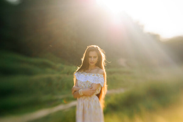 Portrait of a young beautiful girl in a sundress. Summer photo session in the park at sunset. Close-up shot.