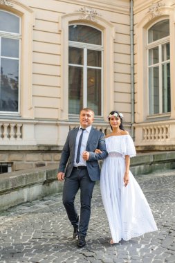 Eski binanın arka planında düğün fotoğrafı var. Gelin ve damat birlikte yürüyorlar. Bir kadın bir erkeğin kolunu tutar. Kırsal ya da boho tarzı düğün fotoğrafçılığı