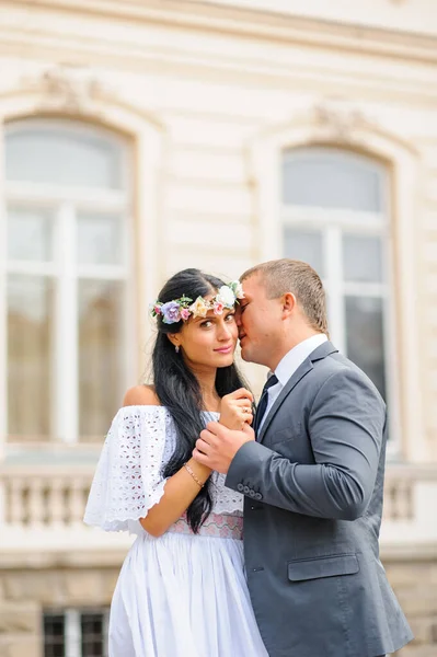 Wedding photo session on the background of the old building. The bride and groom hold each other\'s hands.