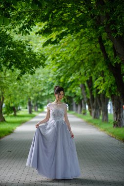 Parkta mavi elbiseyle poz veren güzel bir kadın..