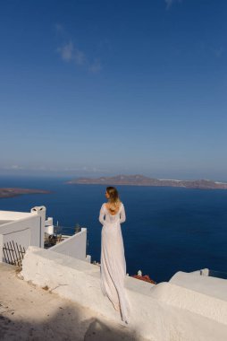 Thira, Santorini 'de Akdeniz' in arka planında poz veren beyaz elbiseli güzel gelin..