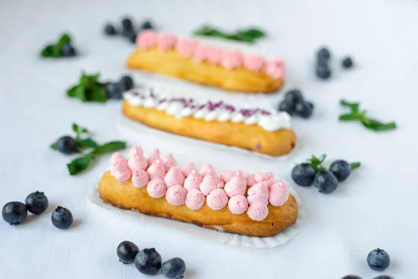 Tasty Homemade Eclairs White Tablecloth Blueberries Scattered Everywhere — Stock Photo, Image