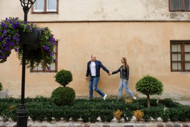 Koca, karısının elini eski duvarda gezdiriyor..