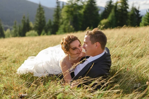 在山上拍婚纱照新婚夫妇躺在草地上 — 图库照片