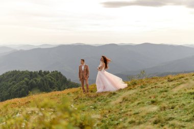 Gelin ve damat, sonbahar dağlarının arka planında birbirlerine yakın duruyorlar..