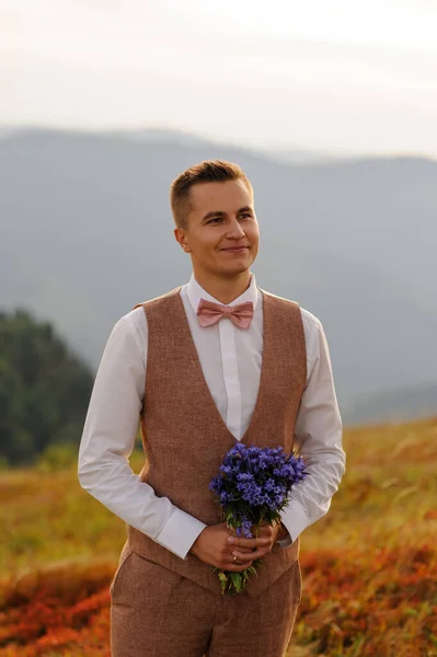 Bir Buket Kır Çiçeğiyle Damat Gelinine Bakar Dağlarda Düğün Fotoğrafçılığı — Stok fotoğraf