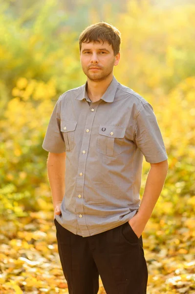 Autumn portrait of a man on a background of yellow autumn. A man is wearing casual clothes.