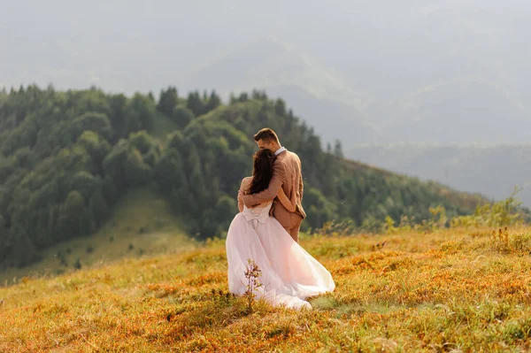 Gli Sposi Abbracciano Teneramente Tramonto Foto Matrimonio Uno Sfondo Montagne — Foto Stock