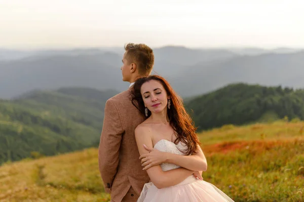 Gli Sposi Abbracciano Teneramente Tramonto Foto Matrimonio Uno Sfondo Montagne — Foto Stock
