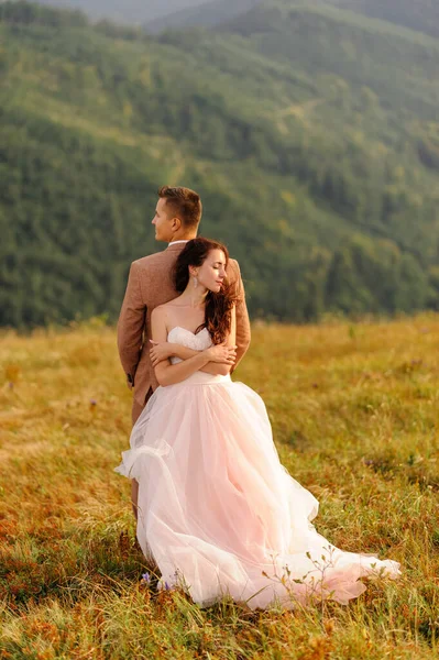 Gli Sposi Abbracciano Teneramente Tramonto Foto Matrimonio Uno Sfondo Montagne — Foto Stock