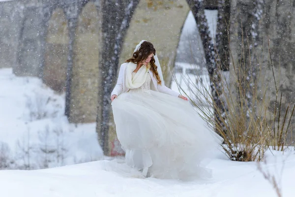 美しい花嫁放棄された古い水路橋の近くにポーズ 花嫁は彼女のドレスを賞賛します — ストック写真