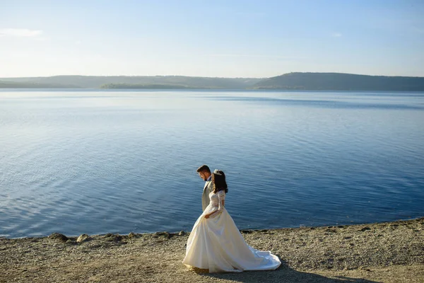 新娘和新郎在湖边散步 — 图库照片