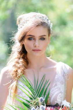 Pembe gelinlikli mutlu gelin. Kız elinde bir düğün buketi tutuyor. Ormanda Boho tarzı bir düğün töreni..