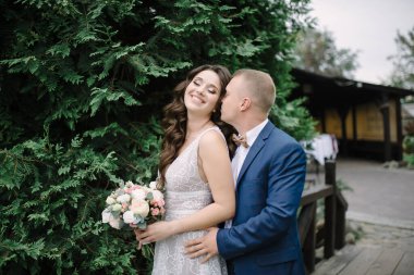 Gelin ve damat. Damat geline sarılır ve onu arkadan öper..