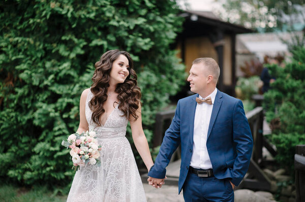 The bride and groom hold hand.