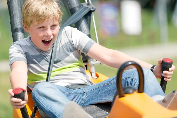 Ευτυχισμένο αγόρι στο τρενάκι του λούνα παρκ πίστα για αγώνες bobsled καλοκαίρι ιππασίας — Φωτογραφία Αρχείου