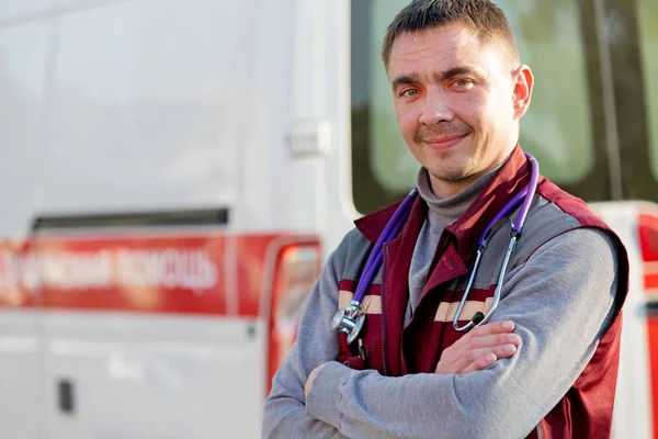 Sonriente paramédico en el fondo de la máquina de ambulancia — Foto de Stock