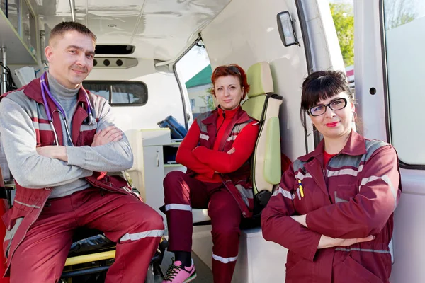 Médecin ER positif avec des collègues paramédicaux dans la voiture d'ambulance — Photo