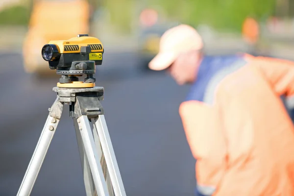 Land surveying equipment theodolite at construction site on industrial worker background during road works