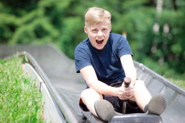 Yazın lunaparkta Bobsled Lunaparkında hız trenine binen mutlu genç çocuk.