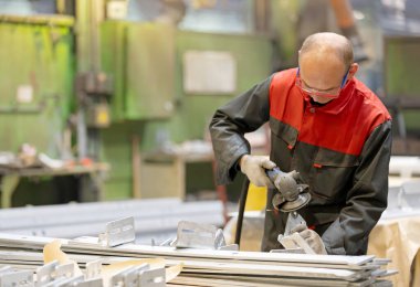 Metal endüstrisi: fabrika işçisi fabrika atölyesinde açı öğütücü kullanıyor