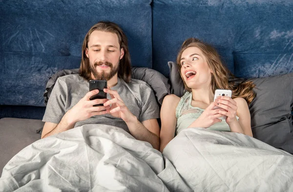 Пара в ліжку зі смартфонами — стокове фото