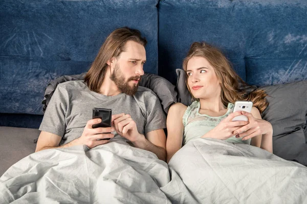 Casal na cama com smartphones — Fotografia de Stock
