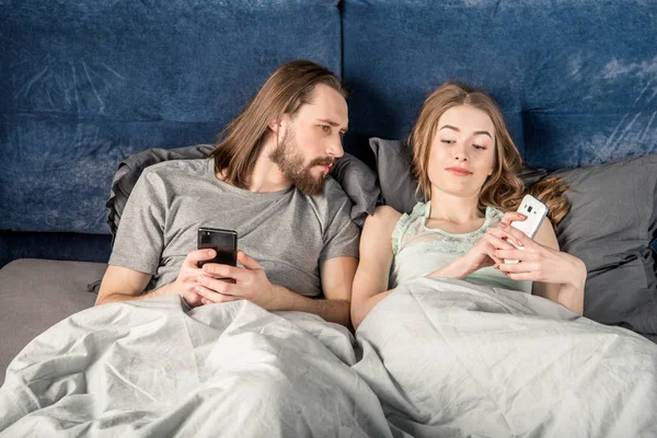 Couple in bed with smartphones — Stock Photo