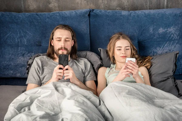 Пара в ліжку зі смартфонами — стокове фото