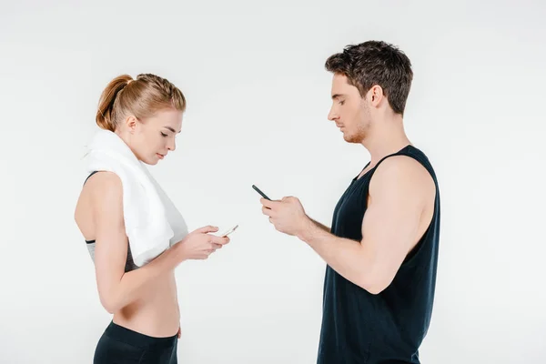 Pareja en forma mirando los teléfonos inteligentes - foto de stock