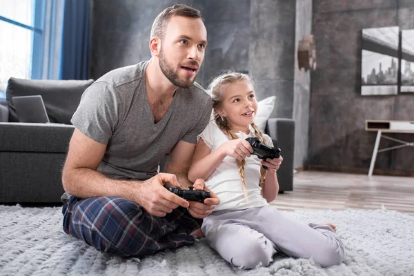 Far och dotter leker med joysticks — Stockfoto