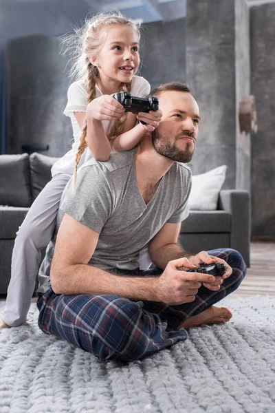 Far och dotter leker med joysticks — Stockfoto