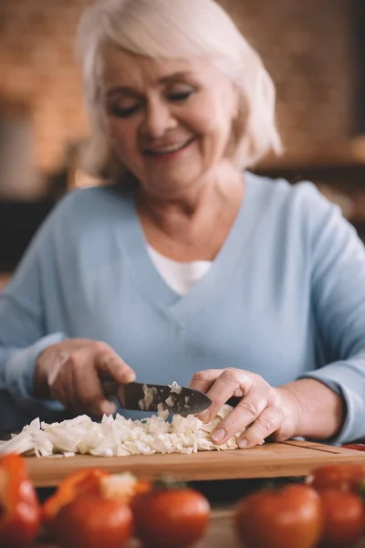 Seniorin schneidet Zwiebeln — Stockfoto