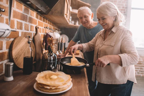Senior couple cooking pancakes — Stock Photo, Image