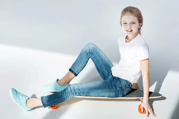 Девушка сидит на скейтборде — стоковое фото