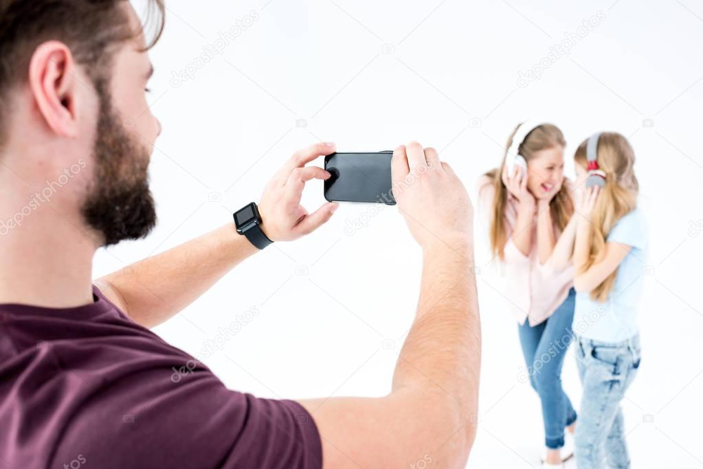 father taking photo of mother and daughter